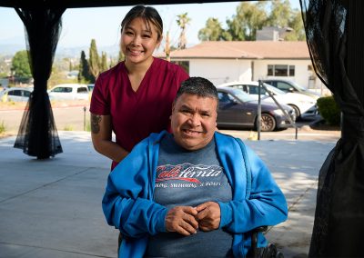 A caregivers with a resident in a wheelchair at the back courtyard of the Valle Vista facility