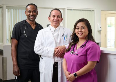 Three caregivers at the nurse's station in the Valle Vista facility hallway