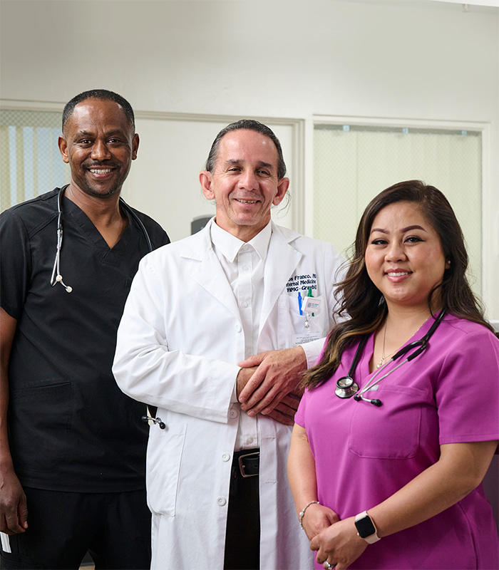 Three caregivers at the nurse's station in the Valle Vista facility hallway